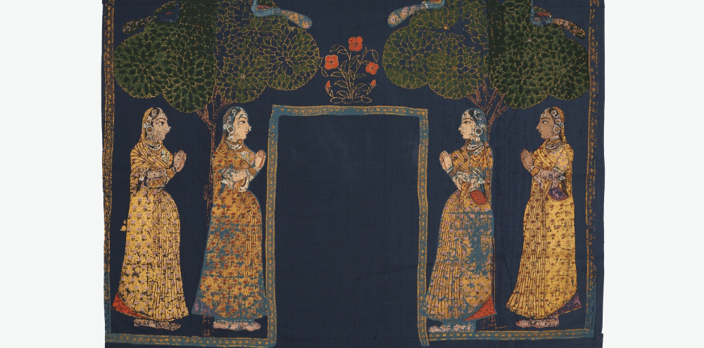 Against a blue background, four women in golden garments stand facing each other in front of two trees with peacocks perched on their branches. The composition is split by a rectangular frame in the middle, with a floral motif on top.