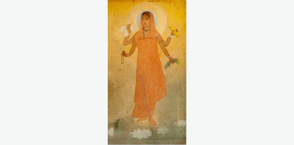 A painting of a woman clad in a saffron garment stands against a hazy background with white lotuses at her feet. Her four arms hold cloth, rosary beads, sacred texts and paddy sheaves.