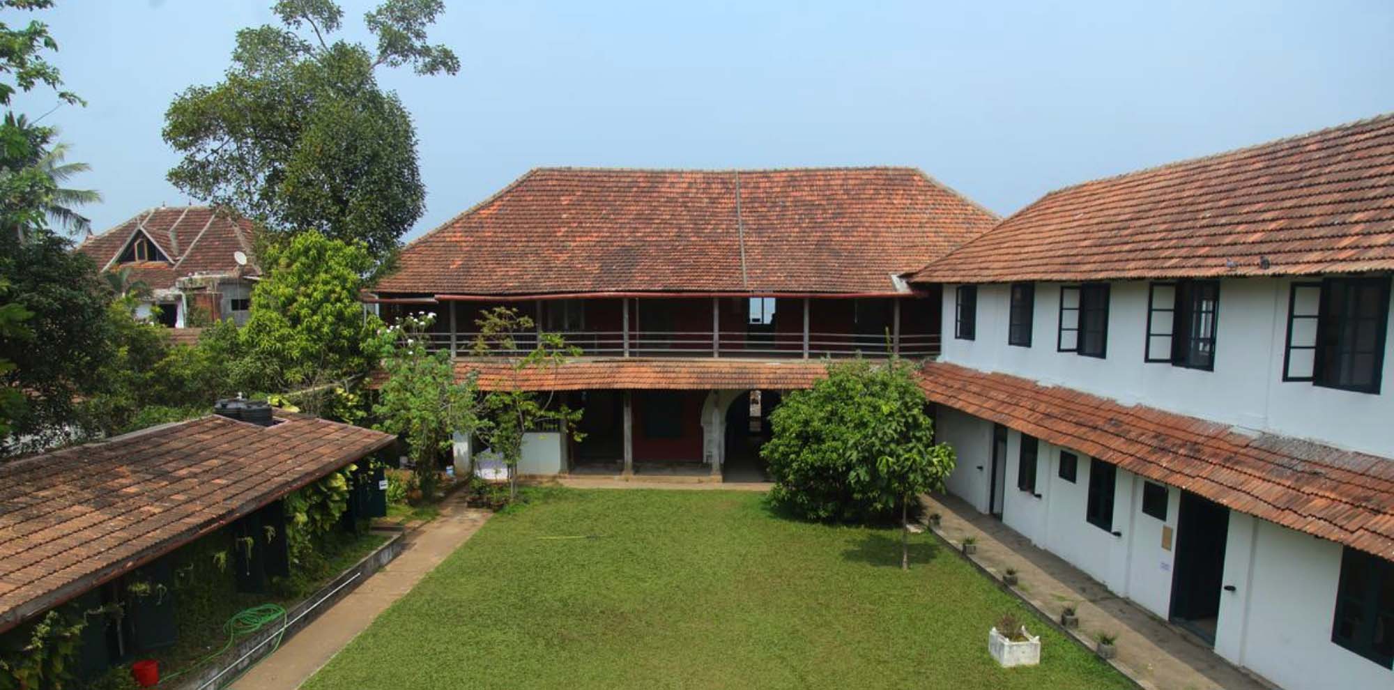 An open inner courtyard of a two-tiered white building with a sloping tiled roof.