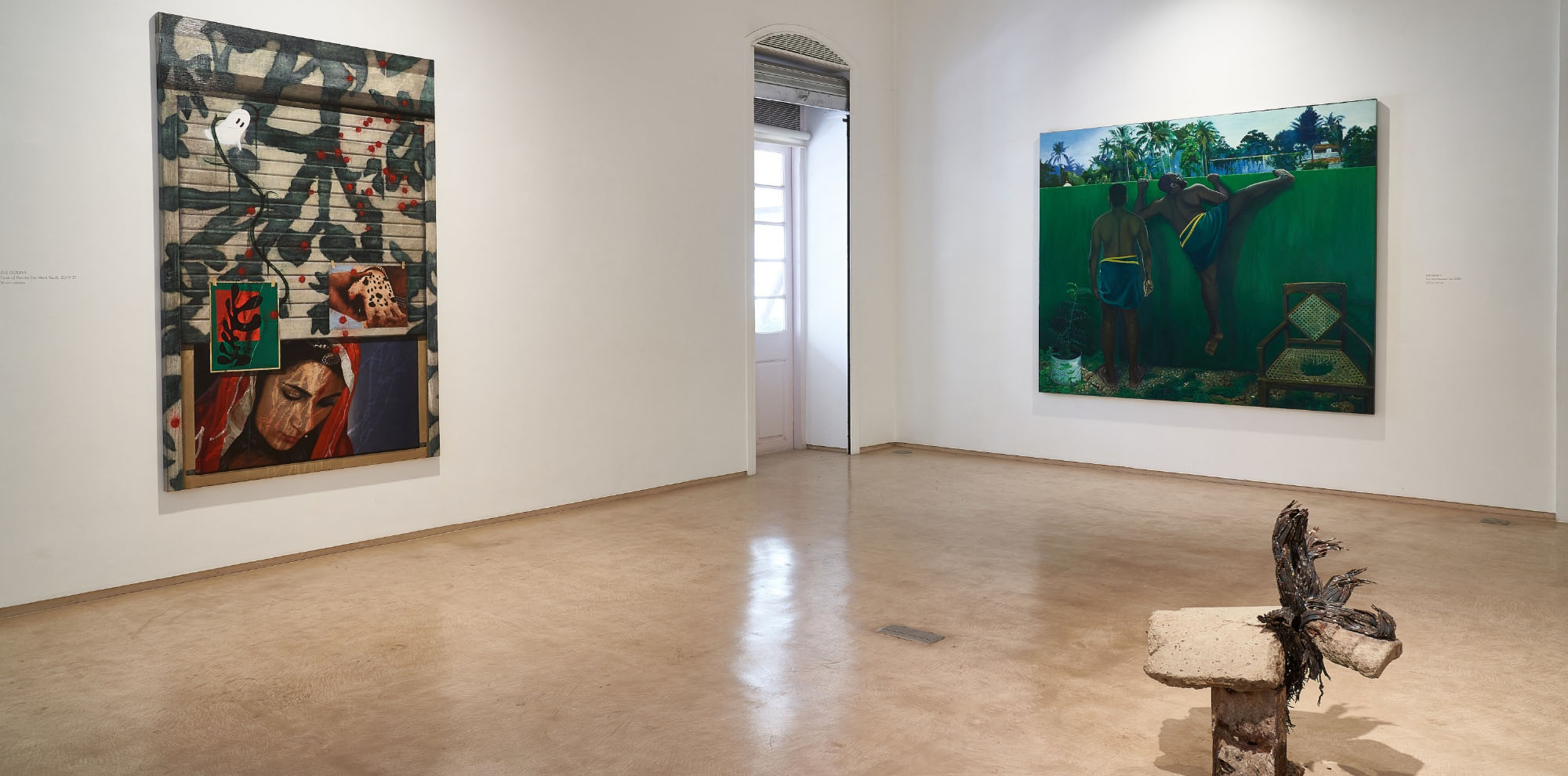 Two large-scale paintings hang on the walls in an exhibition room with a small sculpture in the foreground.