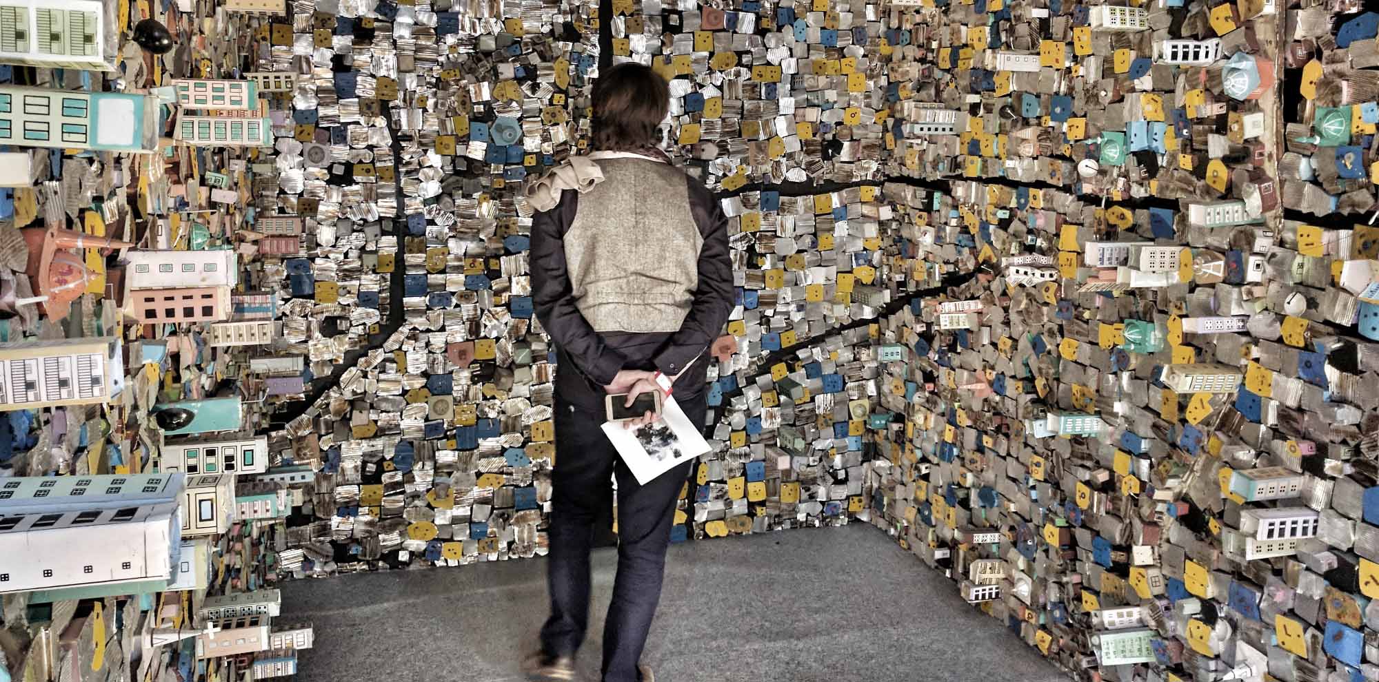 A person observes a protruding wall architectural model of densely packed buildings.