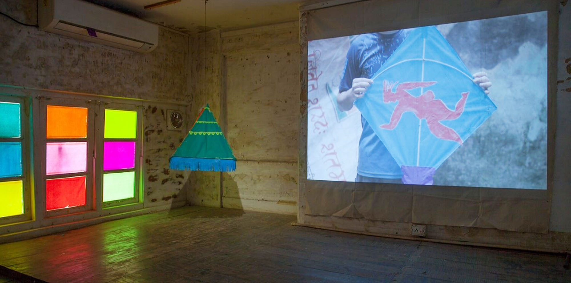A video projection of a boy holding a kite on the wall in a room with stained glass windows.
