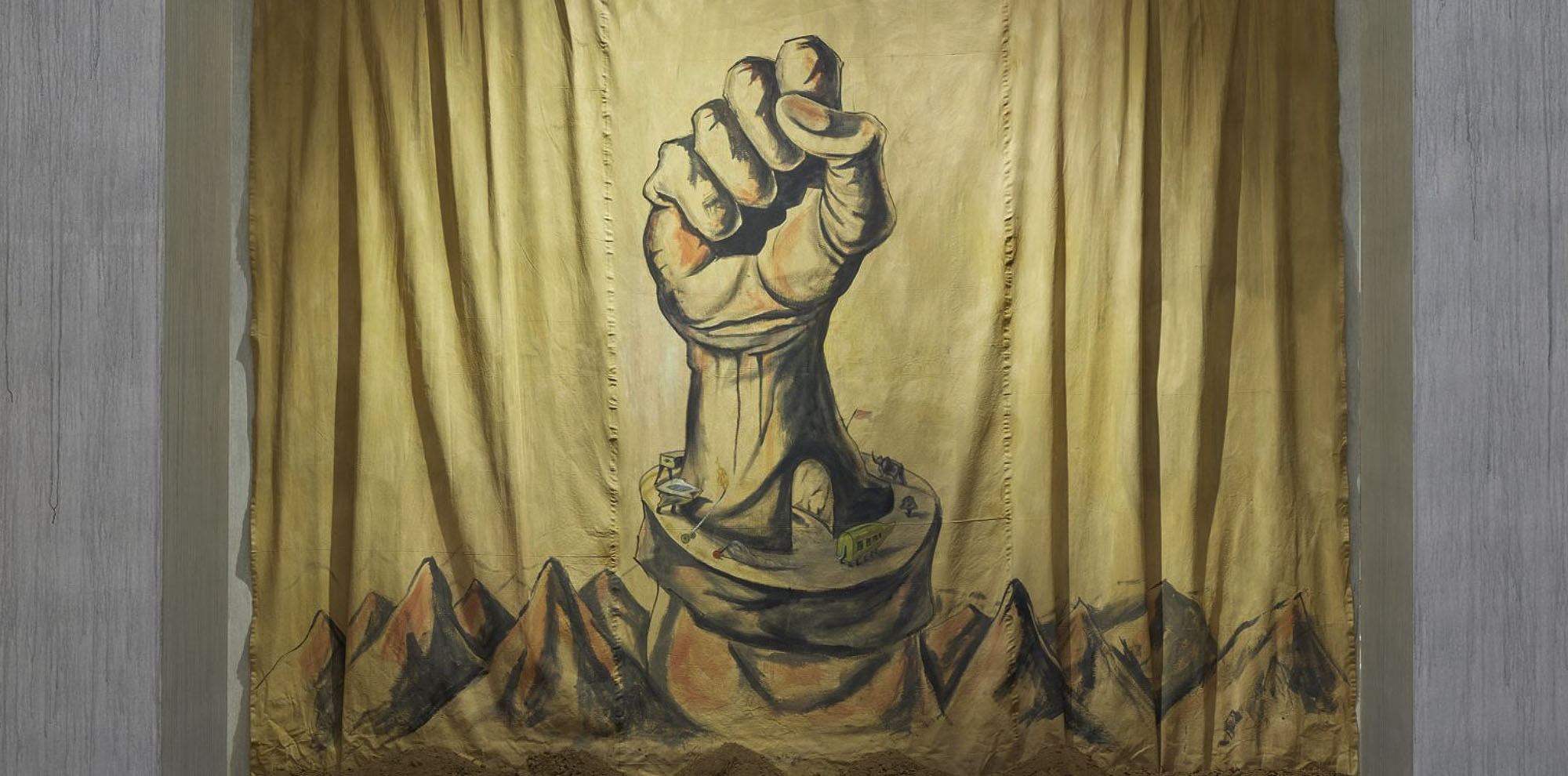 A loosely hung canvas depicting a large clenched fist rising out of mountain peaks.