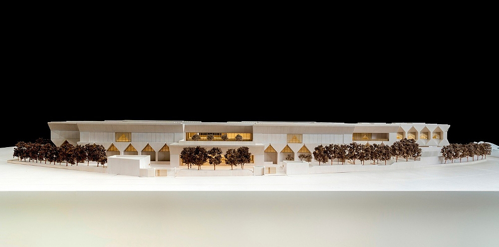 An architectural model of a large building in white paper.